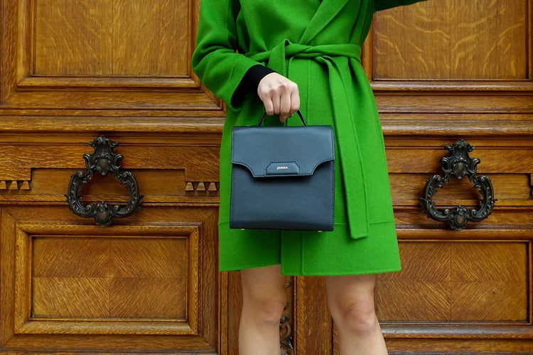 a woman in a green coat holding a black bag