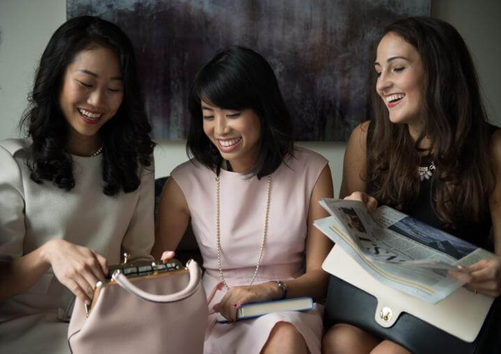 a group of women sitting on a couch looking at a magazine
